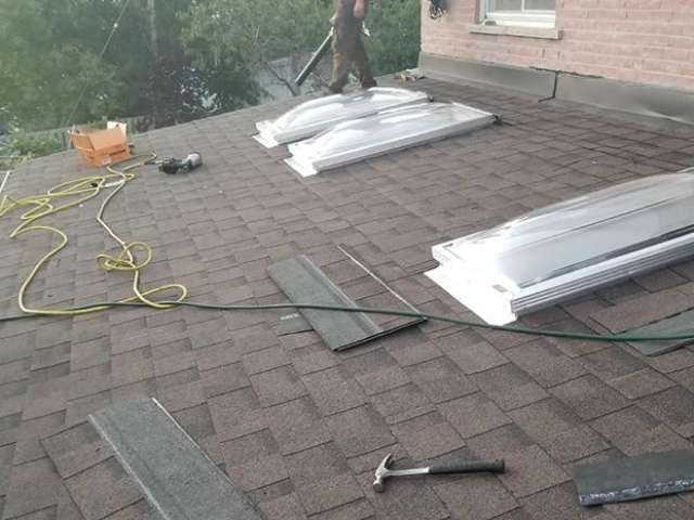 Roof installation with skylights underway.